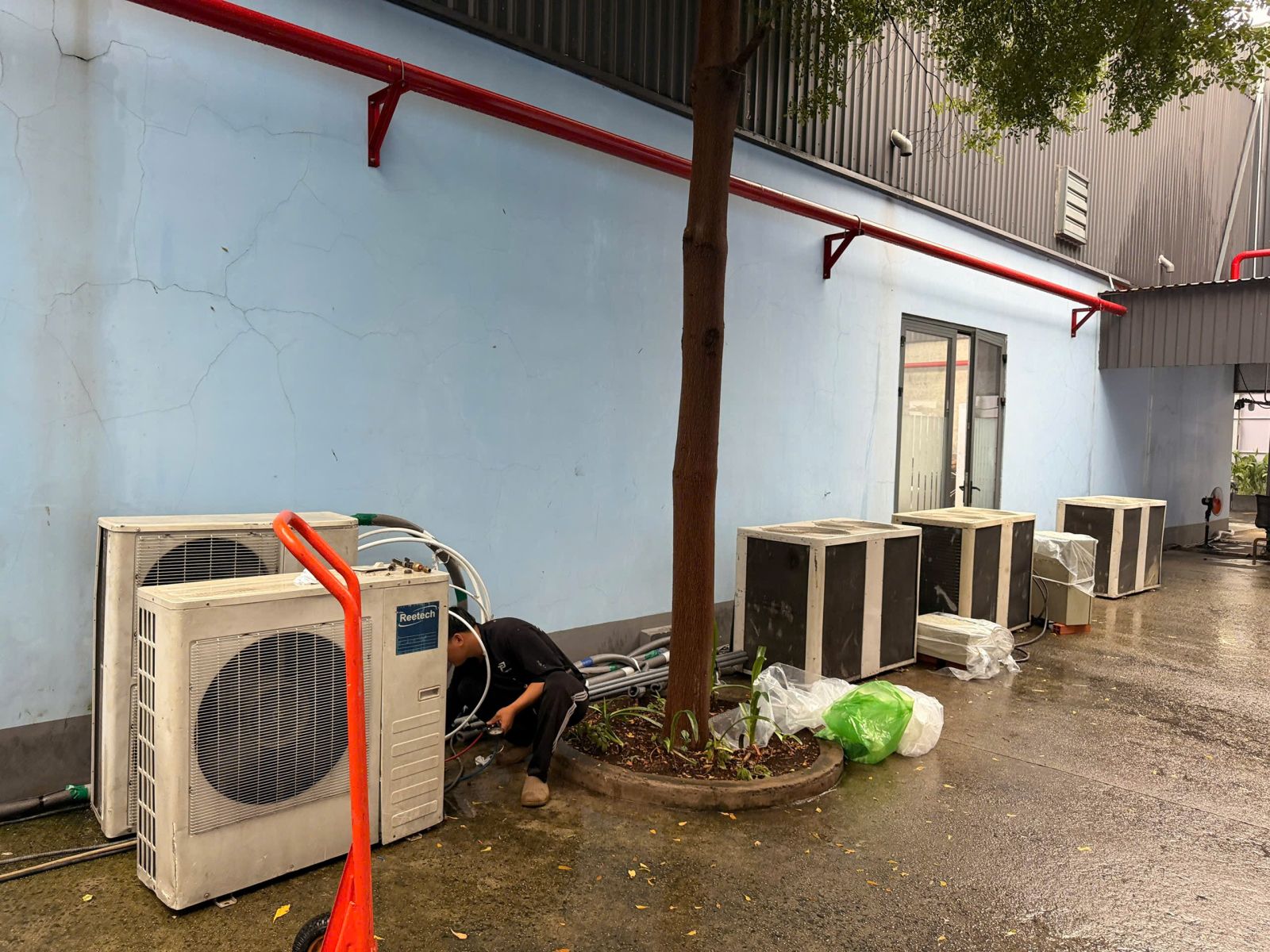 Giá Thuê Máy Lạnh Công Nghiệp: Góc bố trí dàn nóng với nhân sự và xe đẩy trong quá trình triển khai tại địa điểm.