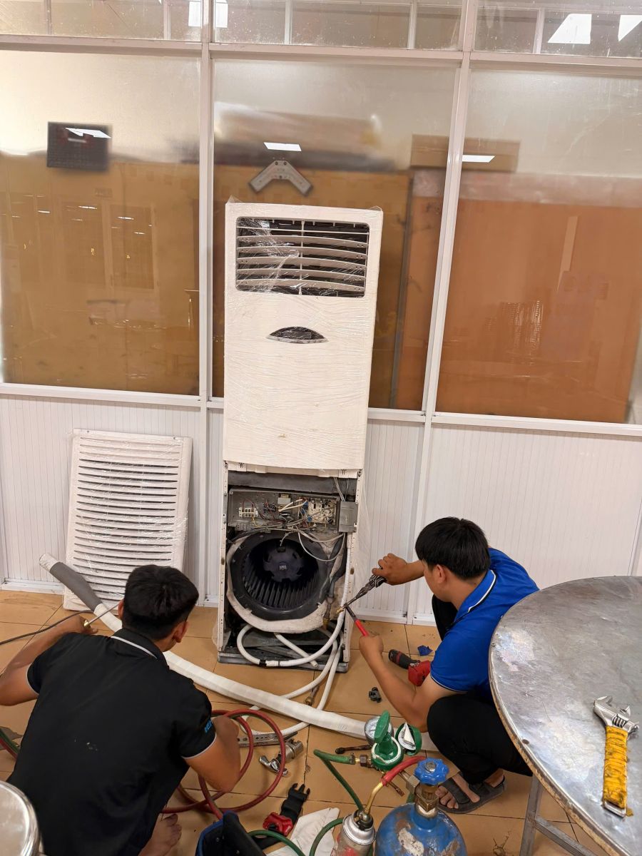 Giá Thuê Máy Lạnh Công Nghiệp: Máy tủ đứng đang mở phần nắp dưới và nhân sự thao tác trước khi hoàn thiện bàn giao.