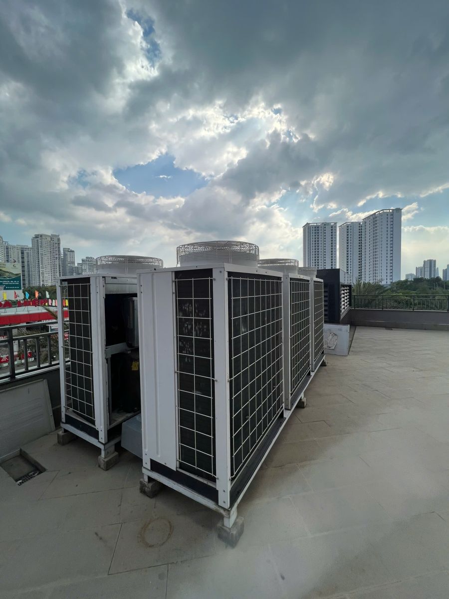 Thanh Lý Hệ Thống Máy Lạnh Công Nghiệp: Các cụm máy có quạt phía trên đặt tại sân thượng, một khoang bên hông đang mở.
